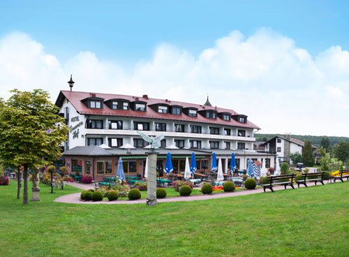 Best Western Hotel Brunnenhof Hotel with outdoor seating area, surrounded by trees and greenery under blue skies.